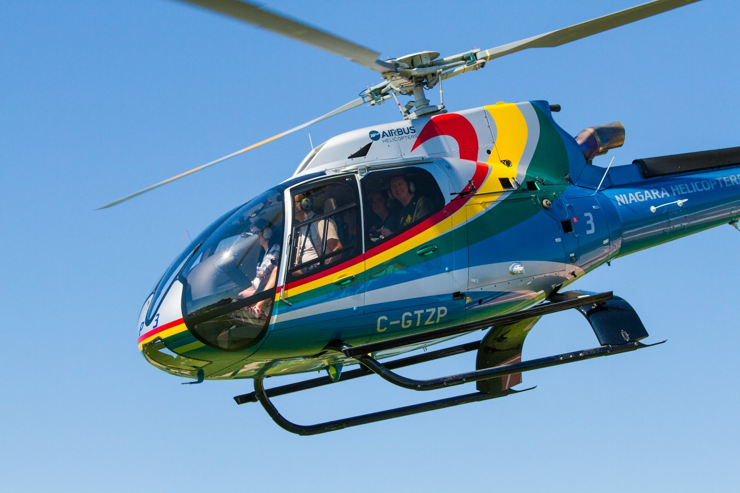 Airbus helicopter flying over Niagara Falls with passengers.