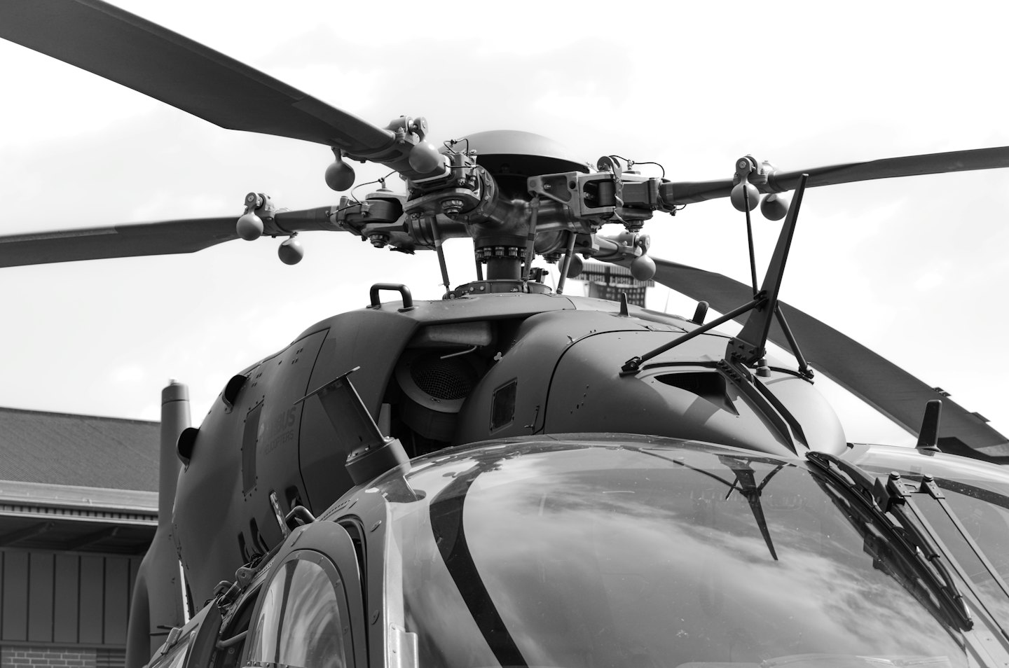 Detailed rotor assembly atop a military helicopter against a cloudy sky.