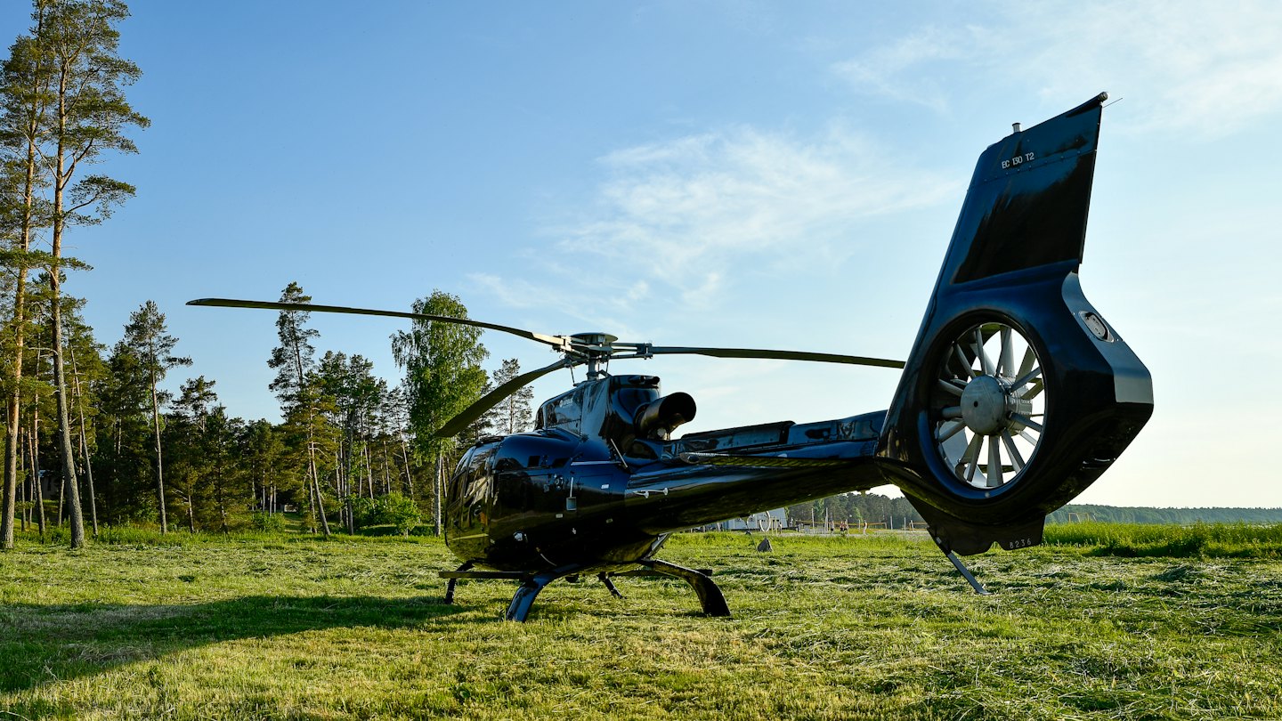 A dark blue helicopter parked on a grassy field.