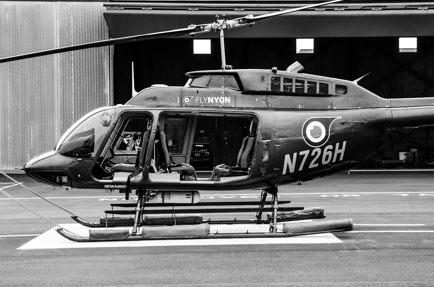 A helicopter parked with open doors on an asphalt helipad.